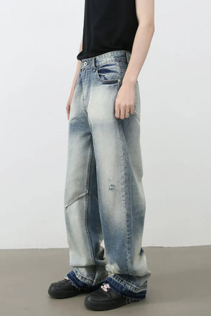 Distressed painterly wide-leg jeans in medium wash denim with paint splatters and ripped details.