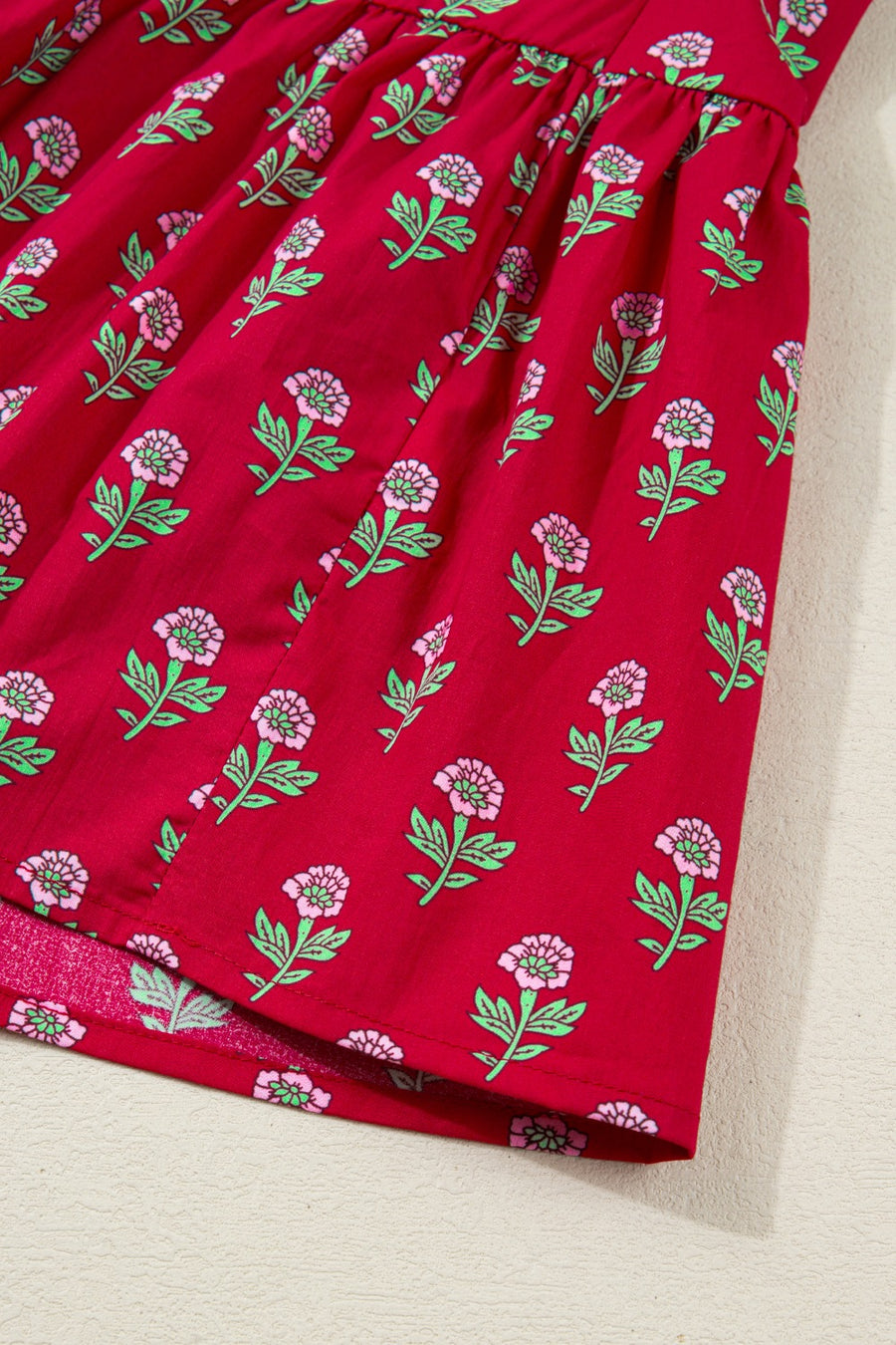Red cotton mini dress with pink floral print and green leaves.