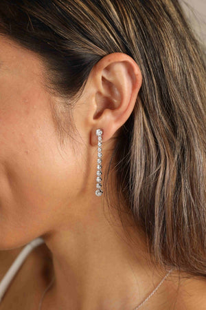 Silver moissanite linear drop earrings with a cascade of sparkling stones.