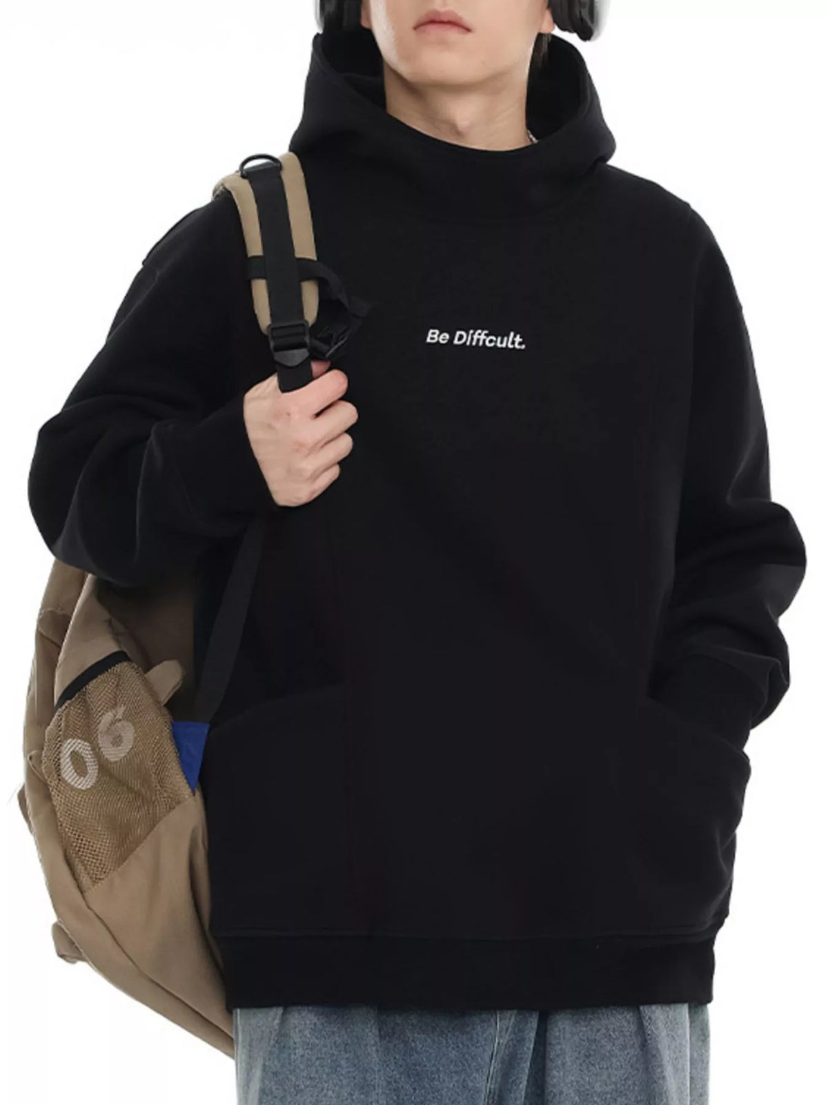 Black oversized hoodie with white embroidered text "Be Difficult." and a front pocket.