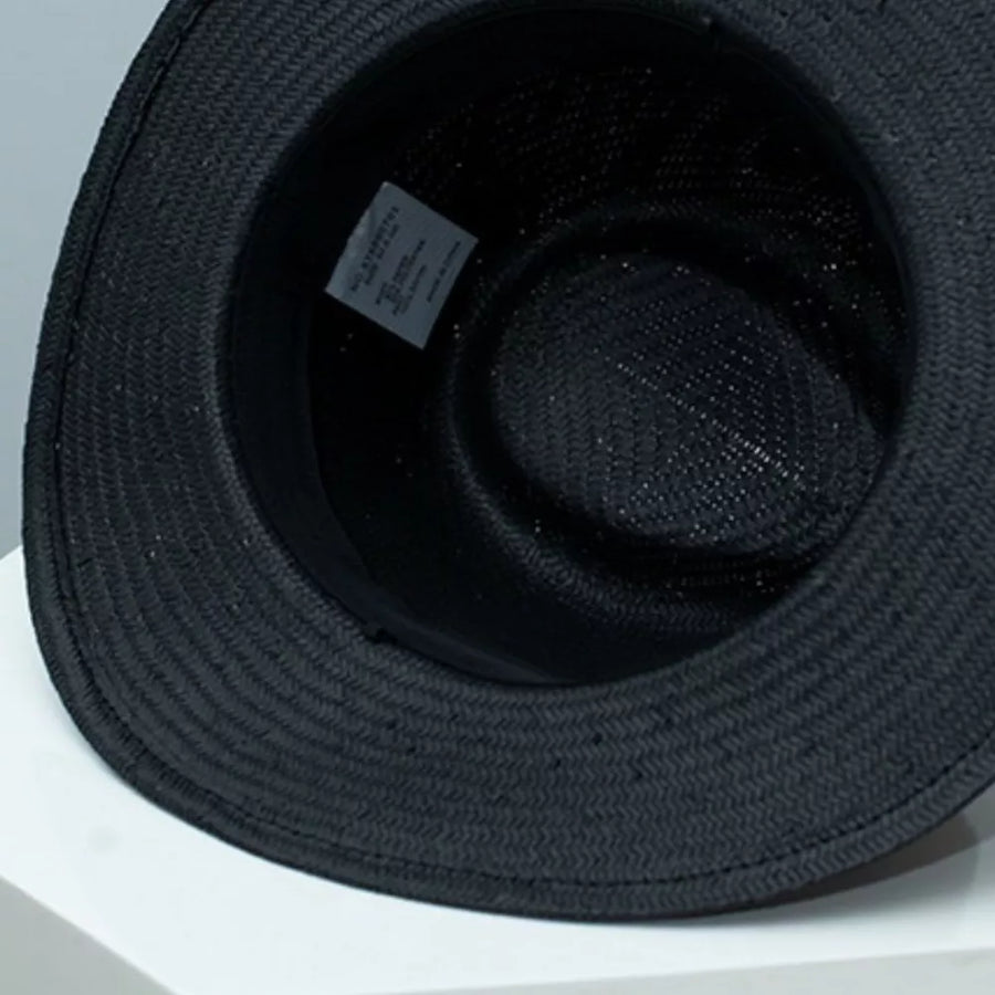 Black straw boater sun hat interior view with woven texture and care label.