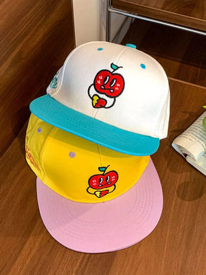 Baseball cap with embroidered apple detail, available in white, yellow, and pastel blue.