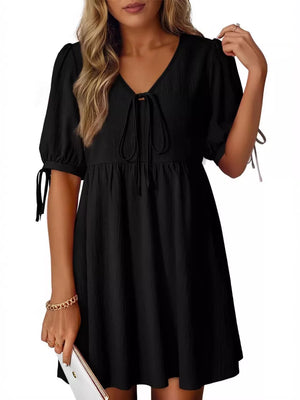 Black mini dress with puff sleeves, tie neck, and tie cuffs.