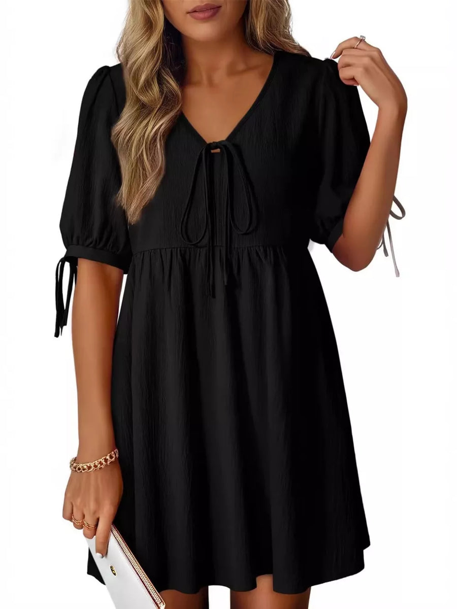 Black mini dress with puff sleeves, tie neck, and tie cuffs.