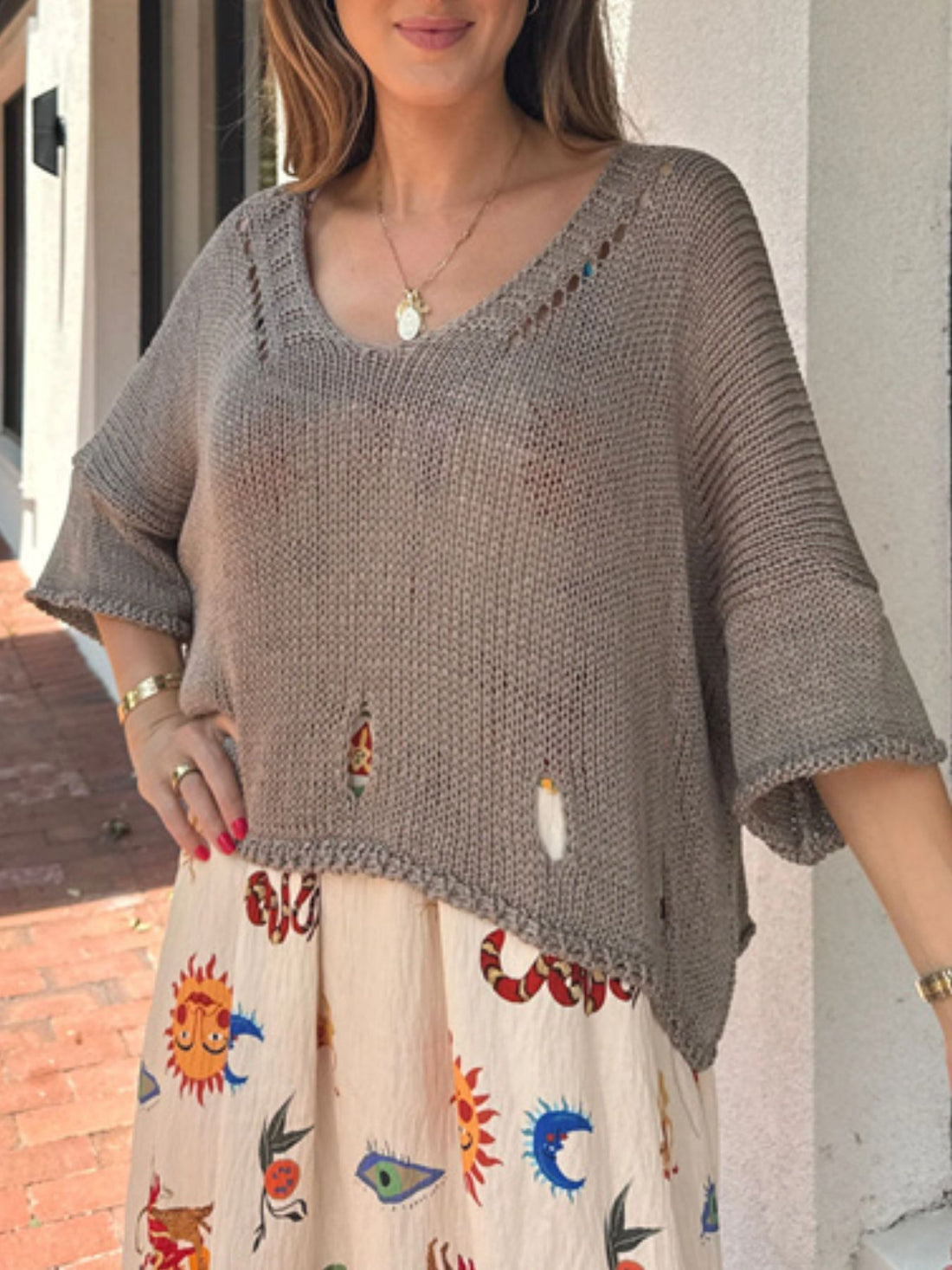 Distressed knit pullover sweater with cutout details and asymmetrical hem.