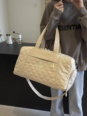 Diamond-stitched beige quilted duffel bag with adjustable strap and front zip pocket.