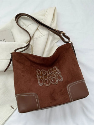 Dark brown suede hobo bag with contrast stitching and appliqué detail.