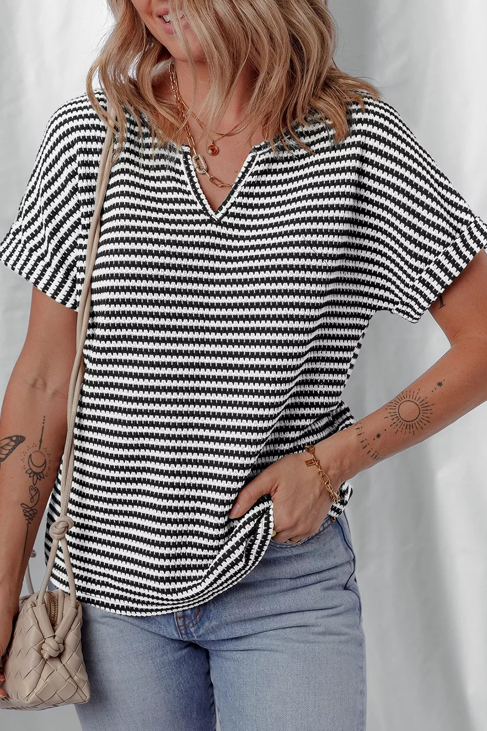 Textured knit t-shirt with notched V-neck and short sleeves in black and white stripes.