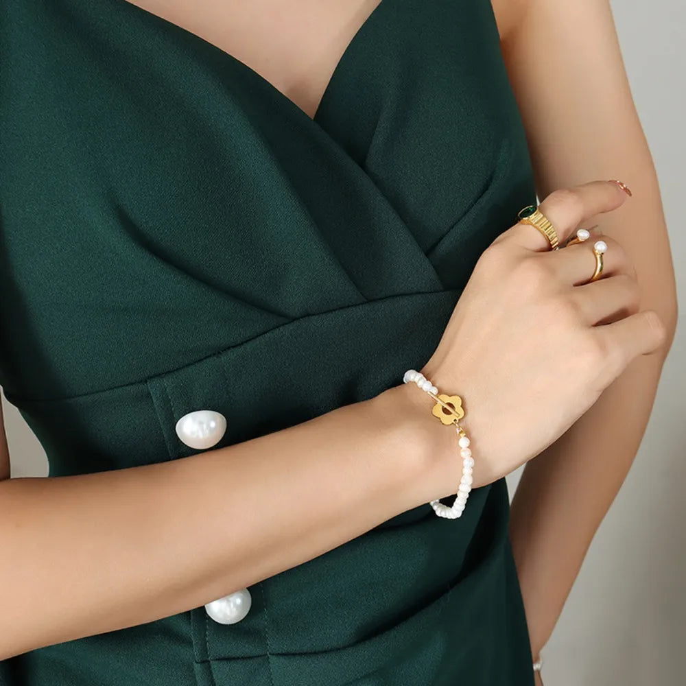 Pearl petal pearl bracelet with gold flower charm on a woman's wrist.