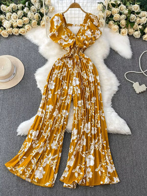 Yellow floral pleated wide-leg romper with V-neck and flutter sleeves.