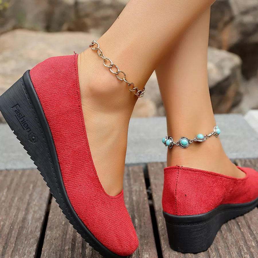 Red textured round toe wedge slip-ons with black wedge sole.