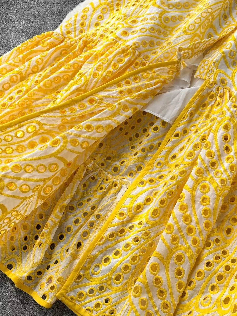 Yellow lace-embroidered tiered cami dress with eyelet details and a white underlayer.