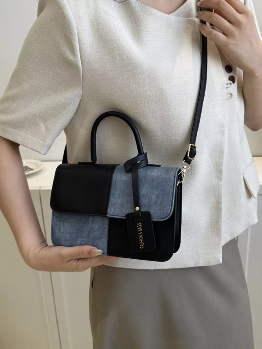 Chic two-tone PU leather crossbody bag with black and denim blue panels and a black tag.