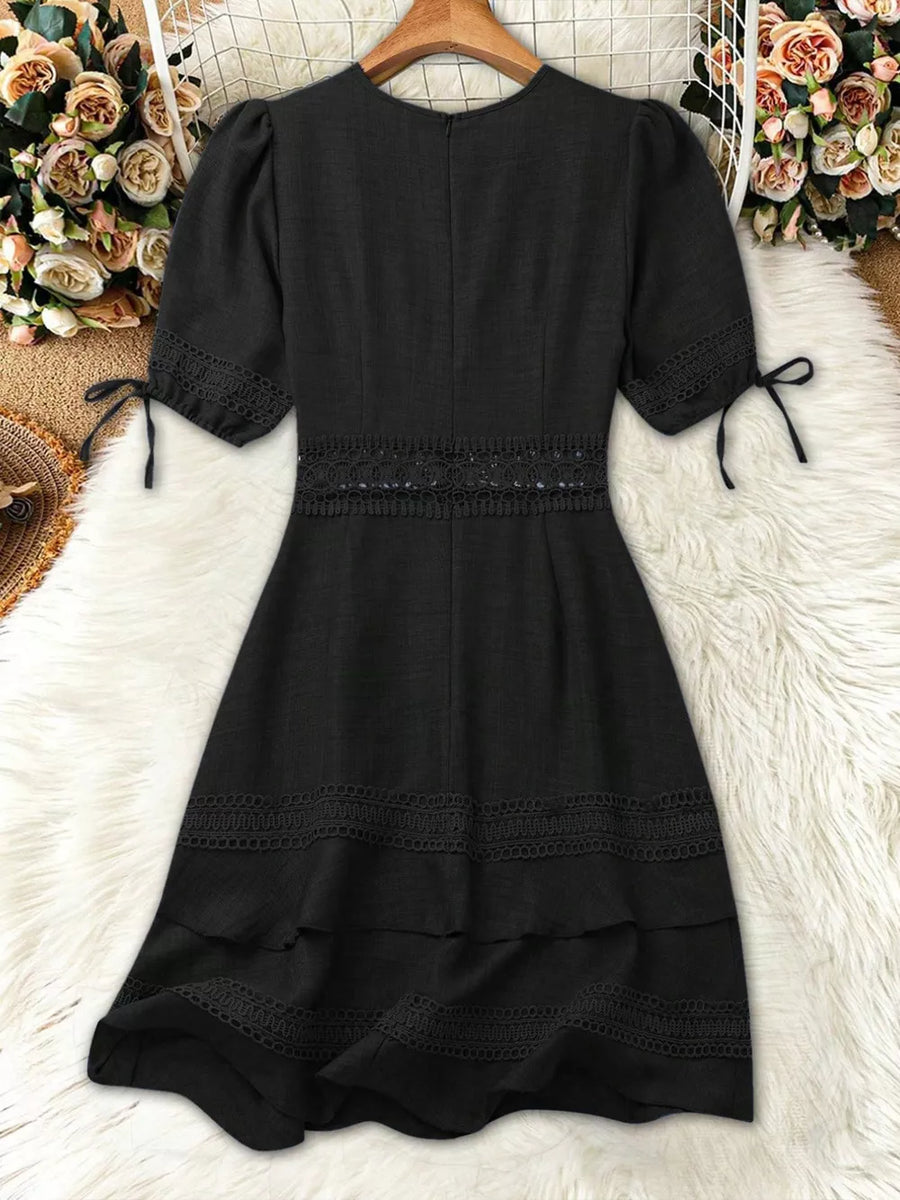 Black lace-embellished V-neck mini dress with puff sleeves and tiered skirt.