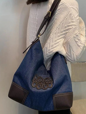 Denim shopper bag with embroidered detail and brown leather trim.