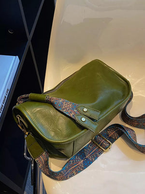 Green textured strap mini crossbody bag with adjustable strap and ornate pattern.