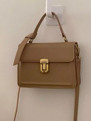 Small coffee pu leather crossbody bag with gold hardware and flap closure.