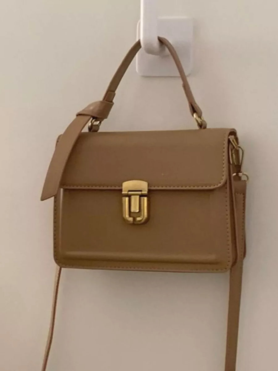 Small coffee pu leather crossbody bag with gold hardware and flap closure.