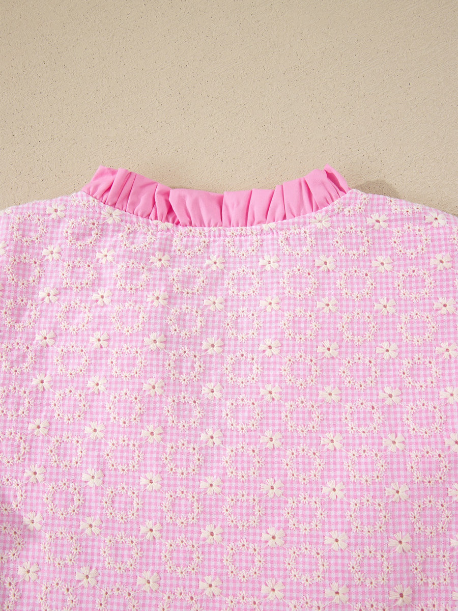 Pink gingham blouse with eyelet embroidery and ruffled neckline.