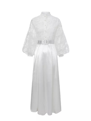 White lace-embellished maxi dress with lantern sleeves, high neck, button front, and white belt.