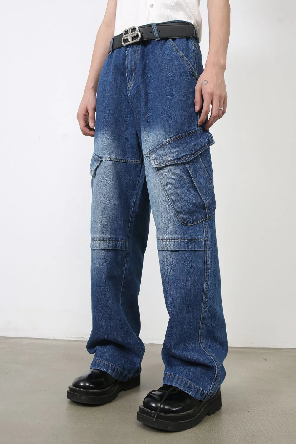 Cargo denim flare trousers in medium wash blue with multiple pockets and a relaxed fit.