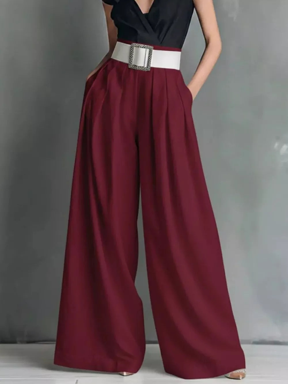 Burgundy maternity pants with a white belt and wide legs.