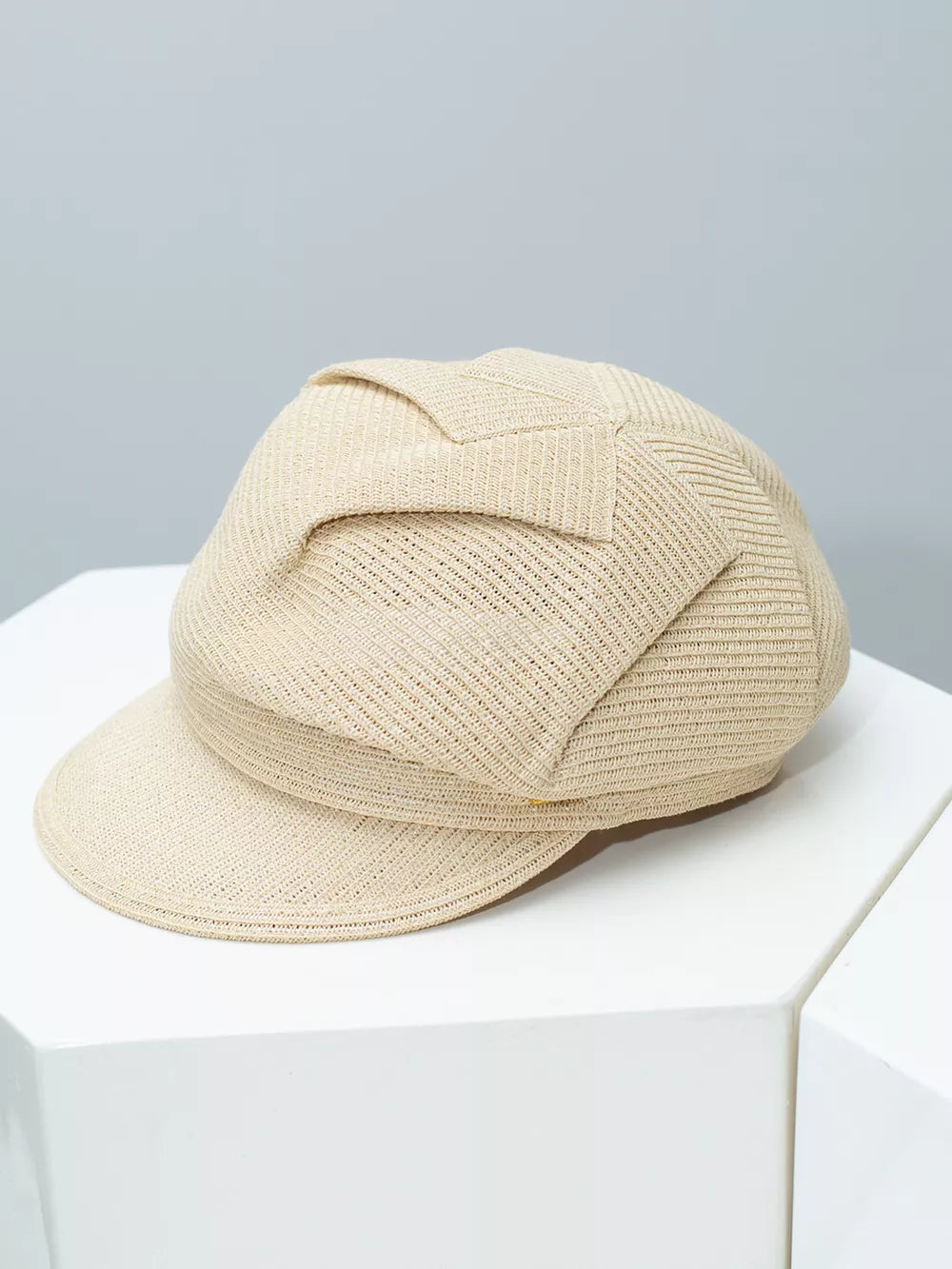 Elegant woven newsboy cap in beige with a textured pattern and decorative band detail.