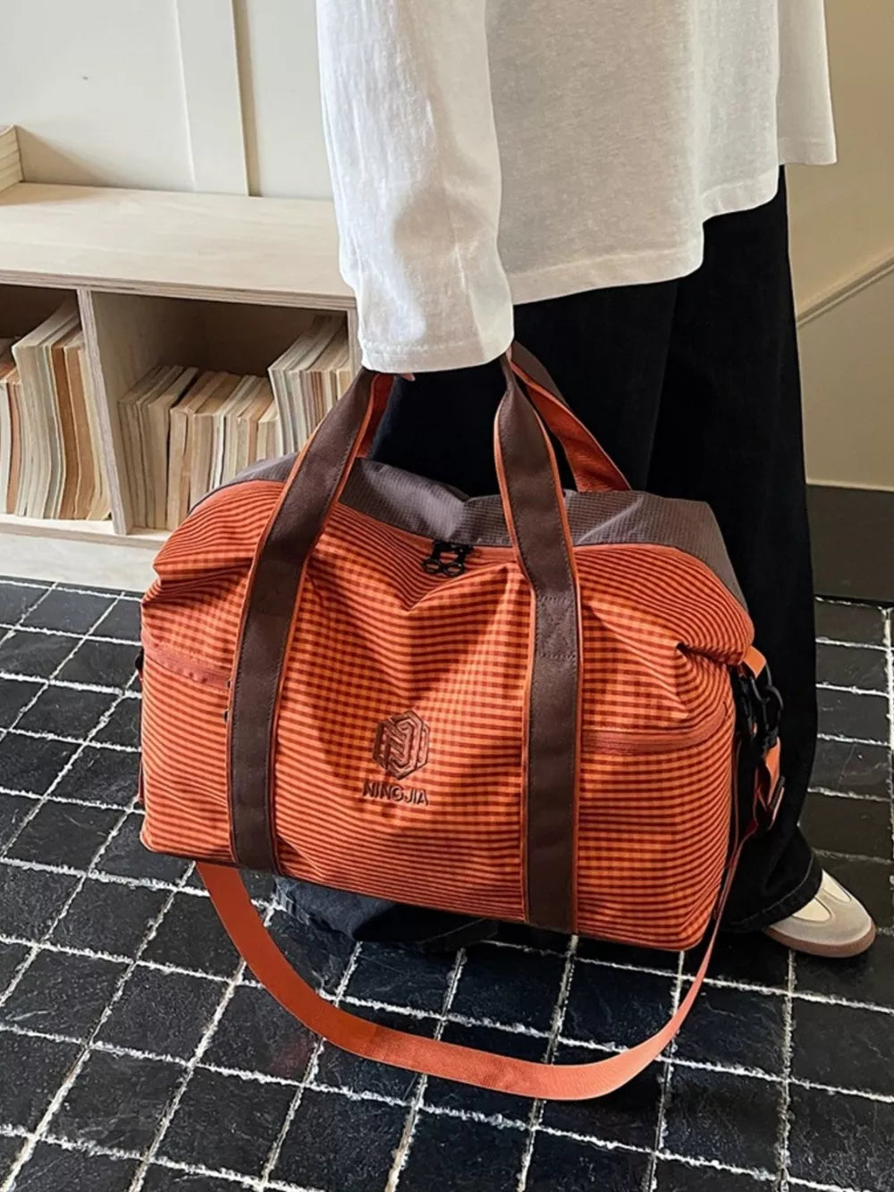 Large orange plaid travel bag with brown straps and logo detail