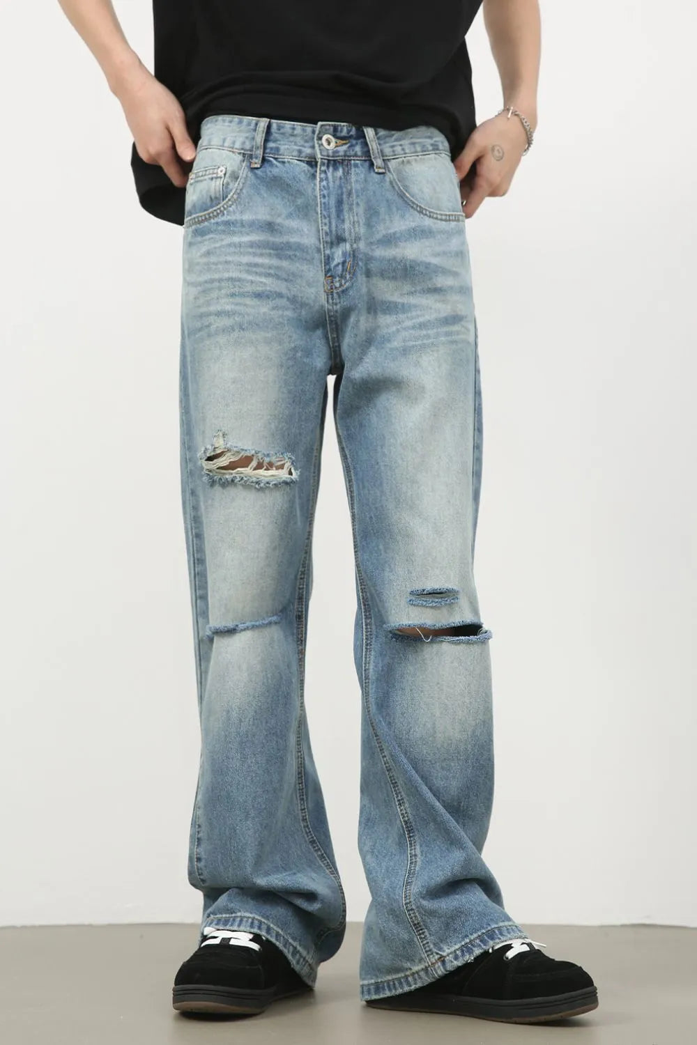 Distressed flare-leg denim jeans in medium wash with ripped details.