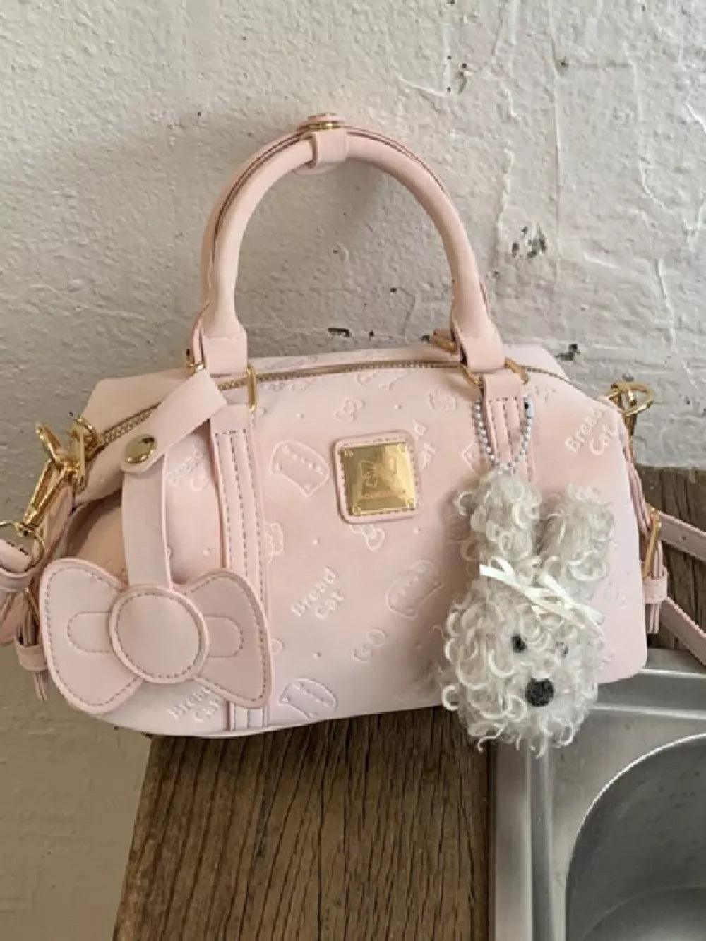 Blush pink crossbody bag with bow detail and fluffy bunny charm