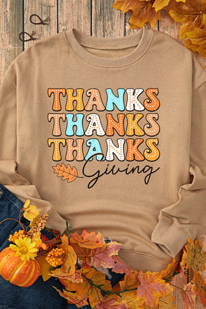 Khaki sweatshirt with colorful Thanksgiving graphic text and a fall leaf accent.