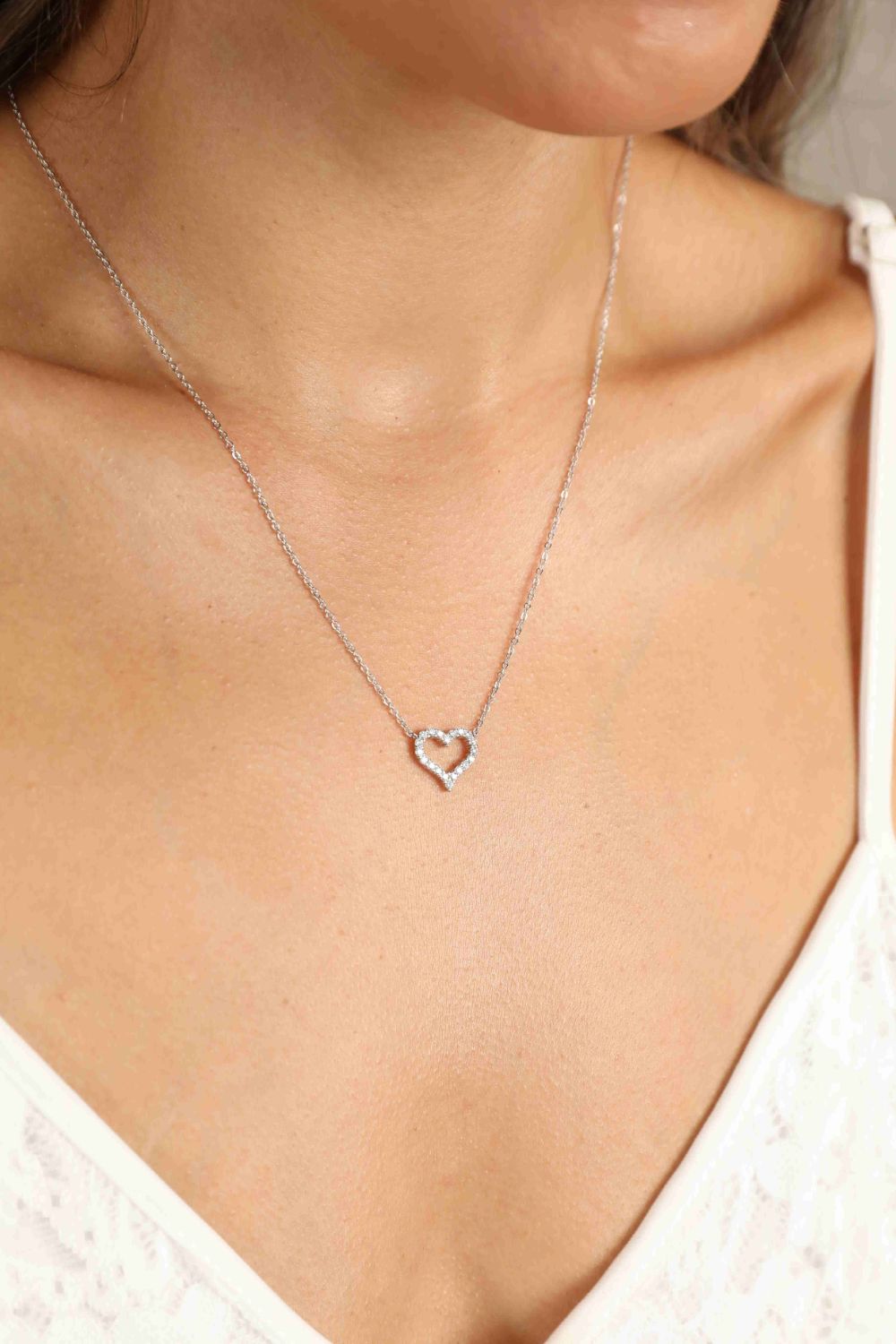 Silver heart pendant necklace with diamond embellishments on a delicate chain.