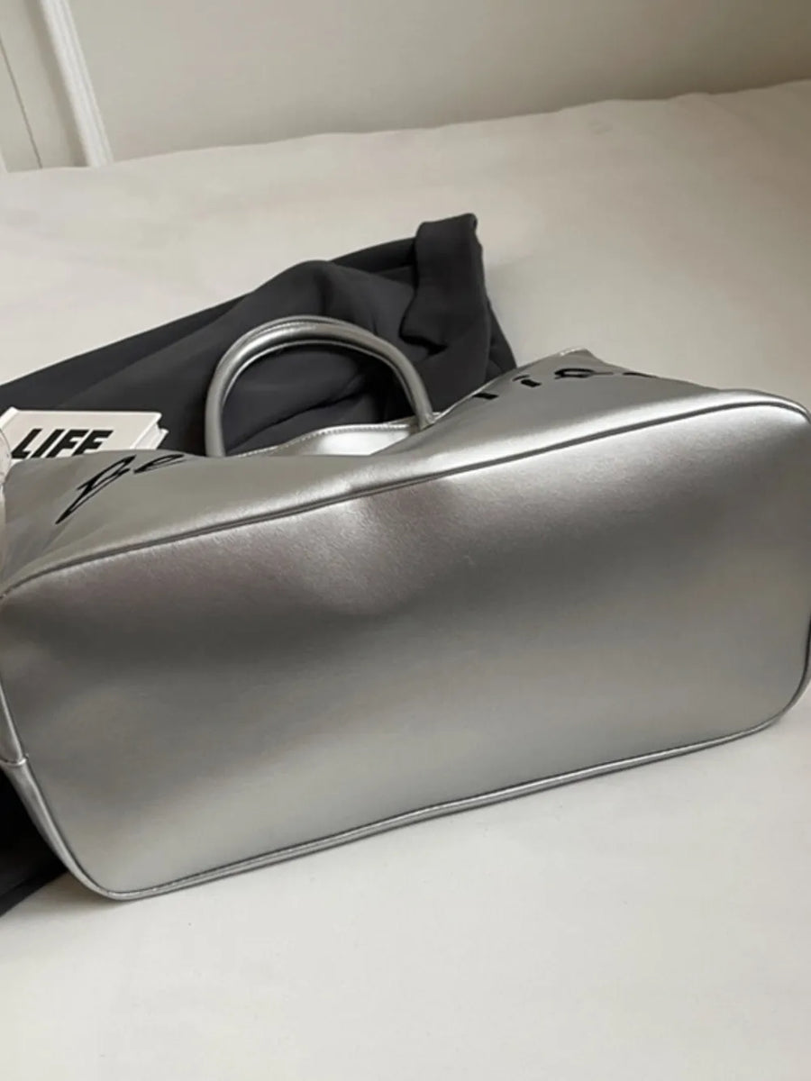 Silver metallic tote bag with black "Better Life" graphic and top handles.
