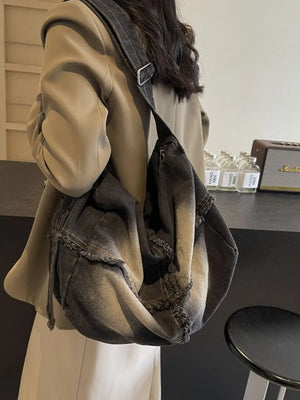 Frayed denim slouch crossbody bag in dark wash with drawstring detail.