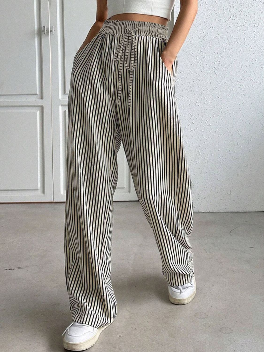 Wide-leg trousers in black and white vertical stripes with a drawstring waist and pockets.