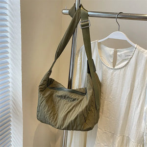 Quilted crescent shoulder bag in olive with a zippered front and adjustable strap.