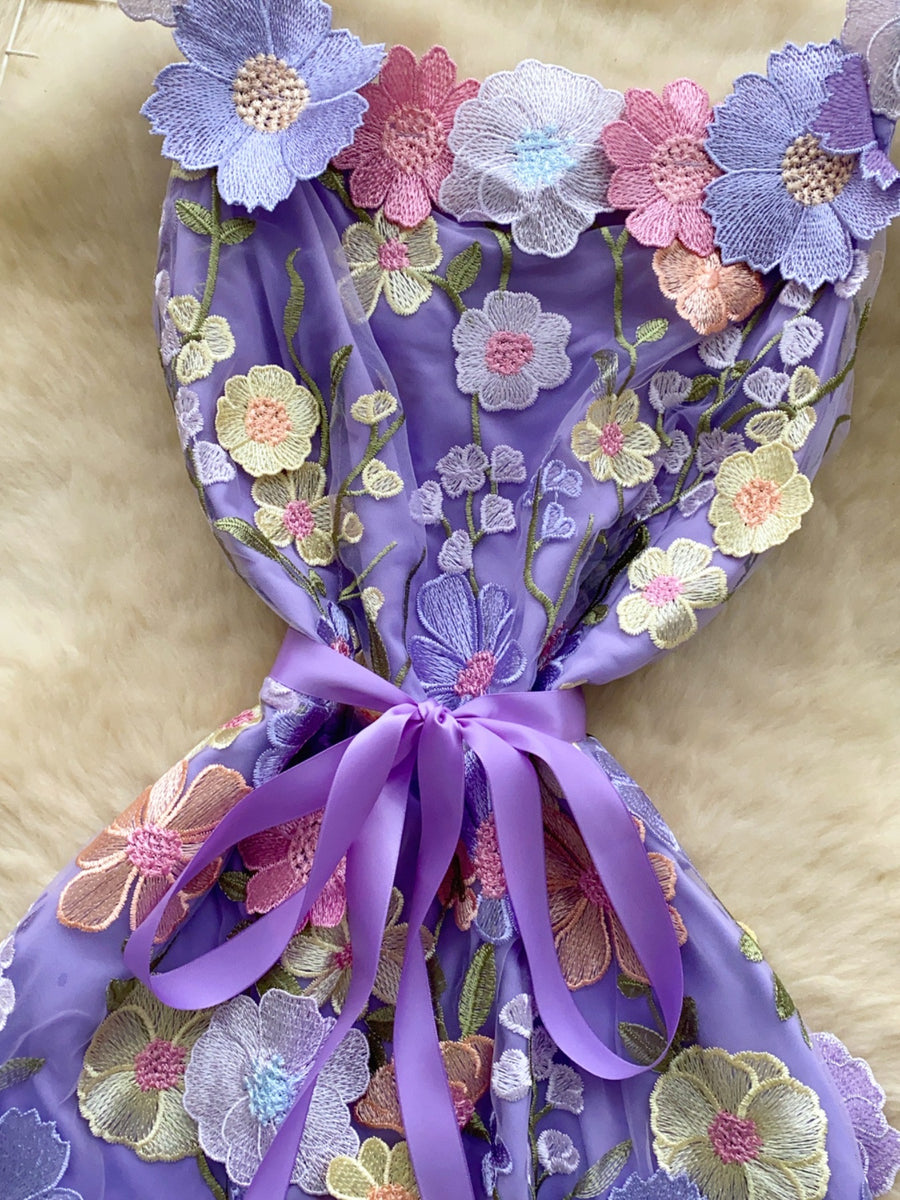 Purple embroidered floral mini dress with a bow detail and colorful flower appliques.