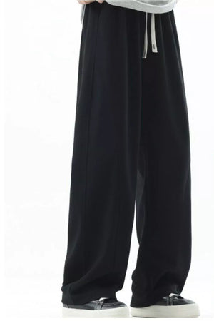 Men's black loose fit sweatpants with drawstring and white laces.