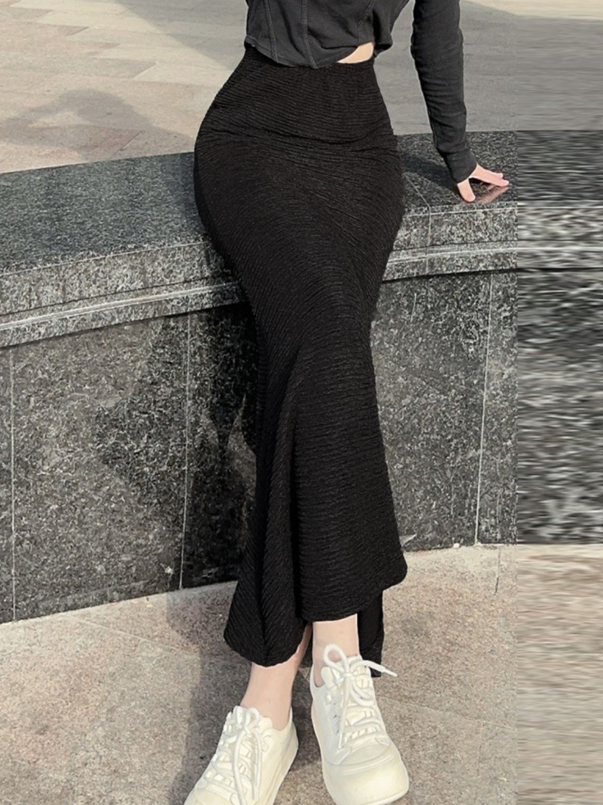 Black textured knit mermaid skirt with a flared hem, styled with white sneakers.
