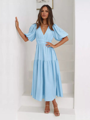 Pastel blue midi dress with puff sleeves, V-neck, and tiered skirt.