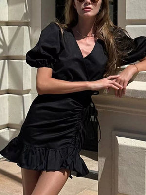 Black wrap dress with puff sleeves, ruched side detail, and ruffled hem