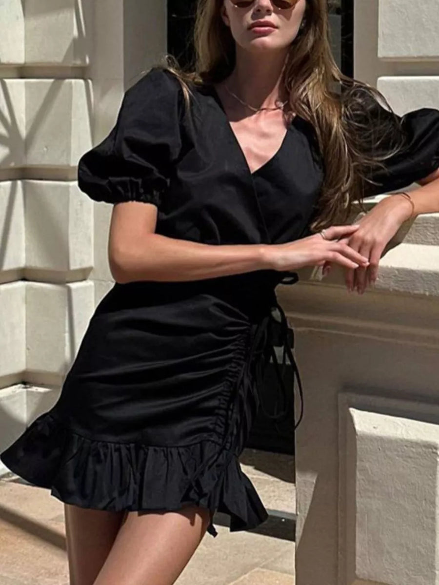 Black wrap dress with puff sleeves, ruched side detail, and ruffled hem