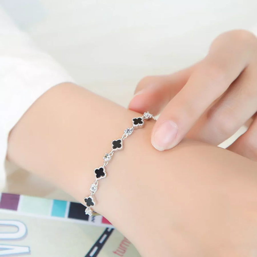 black bracelet featuring clover charms and clover motif