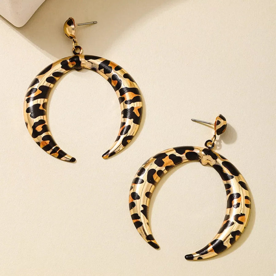 Crescent dangle earrings in gold with leopard print pattern.