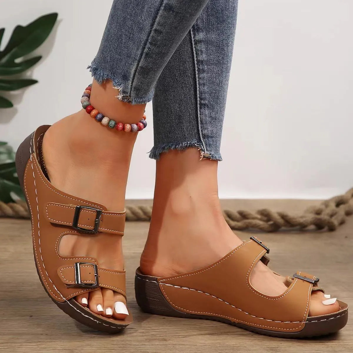 Brown double-strap buckle slides with white stitching and adjustable buckles.