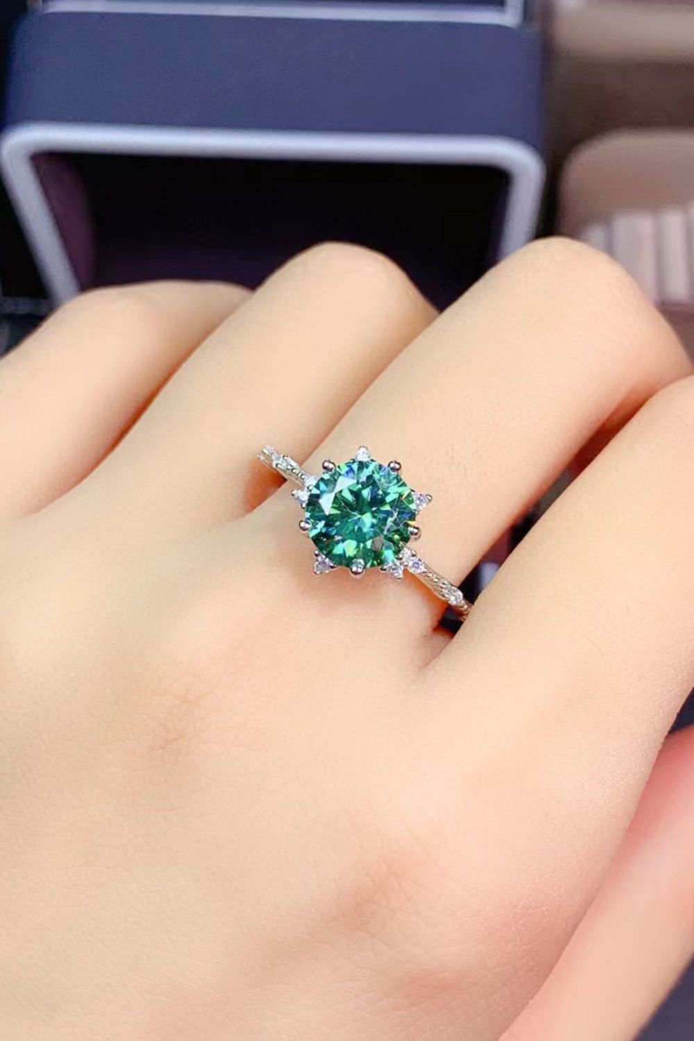 Emerald cut moissanite platinum ring with celestial halo in green.
