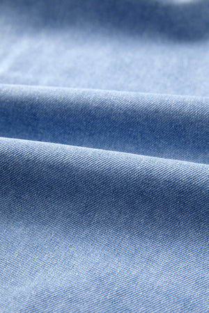 Light blue distressed denim fabric with soft folds and texture.