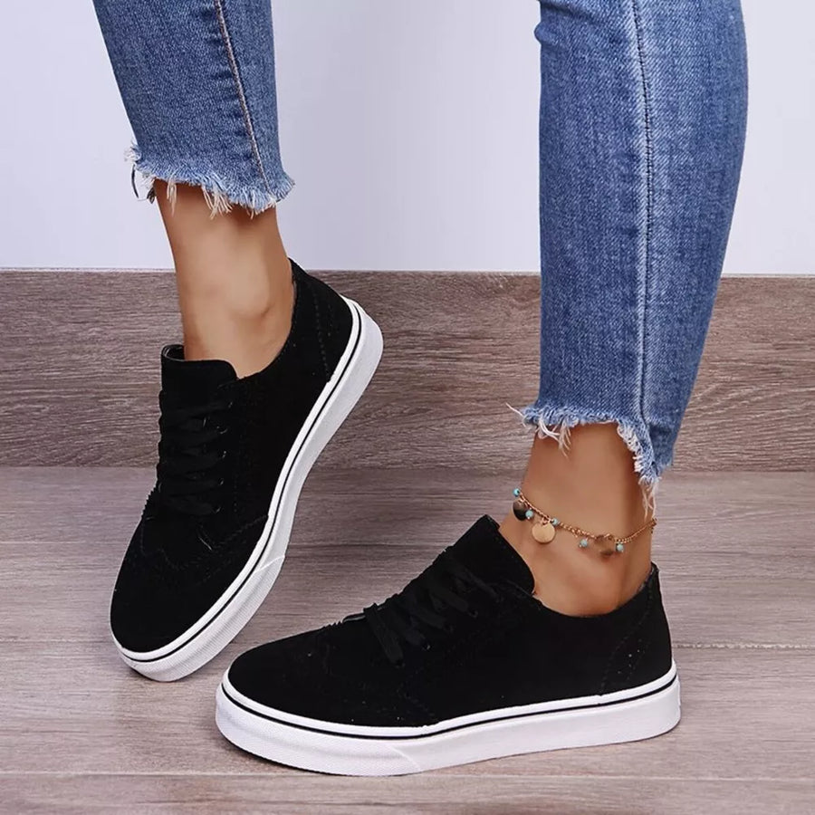 Black matte finish lace-up sneakers with white soles and wingtip detail.