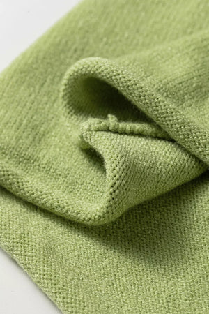 Light green knit sweater with a textured weave and folded hem detail.