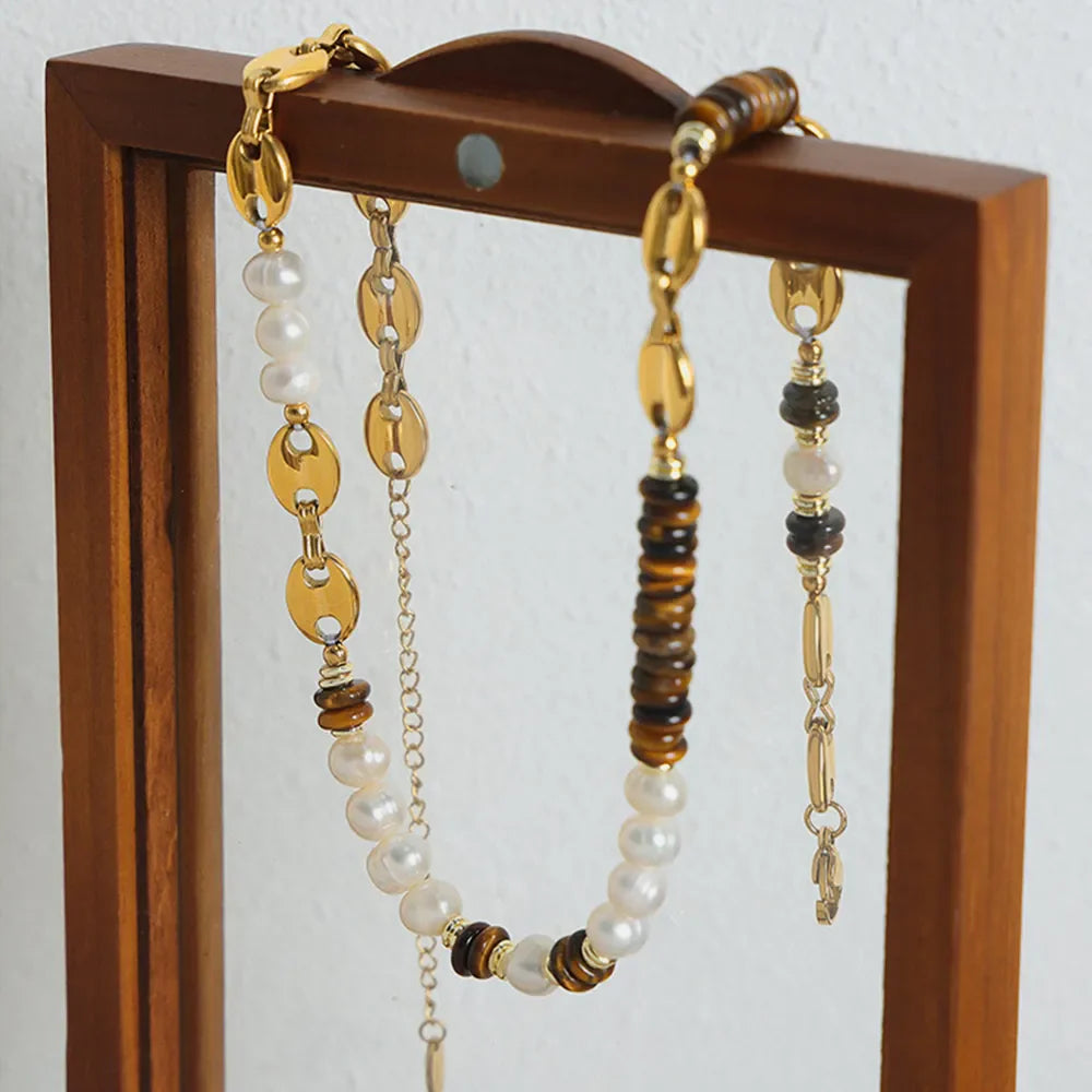 Gold pearl and tiger eye statement necklace with oval links and chain details.